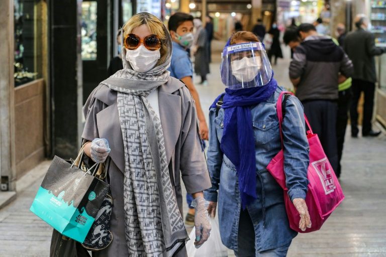 Los compradores vestidos con equipo de protección, incluyendo máscaras faciales y guantes de látex, caminan por el Bazar Tajrish en la capital de Irán, Teherán, al comienzo del mes sagrado musulmán del Ramadán.